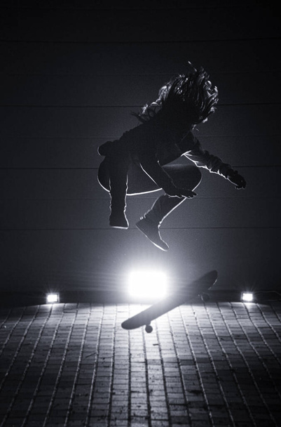 RAJHRAD, CZECH REPUBLIC - Mar 01, 2021: Guy jumping on skateboard in the night with backlights. - Zdjęcie, obraz