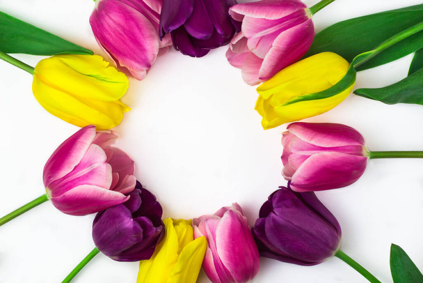 Um buquê de tulipas de flores rosas, amarelas e roxas formando uma moldura para o texto. Vista de cima. Um lugar para texto. - Foto, Imagem