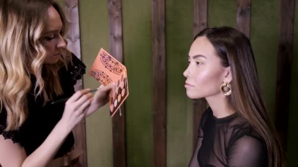 meikki taiteilija tekee meikki houkutteleva nuori aasialainen nainen kauneushoitola - Materiaali, video