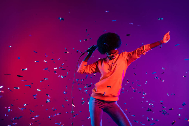 Photo of funky crazy lady dance hold mic confetti fall wear sweatshirt sunglass isolated gradient neon background - Фото, изображение