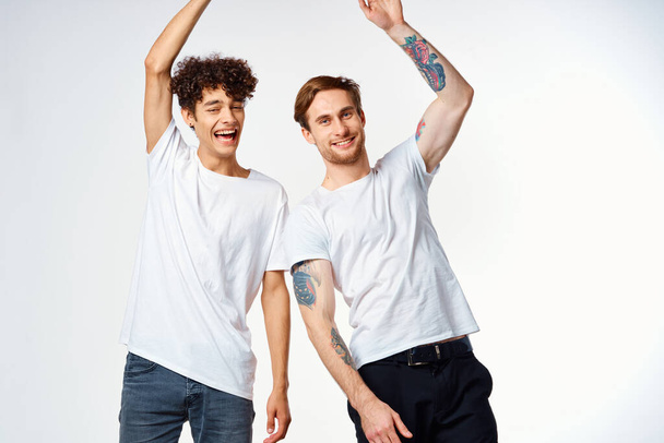 Двое мужчин в белых футболках стоят рядом с эмоциями дружбы - Фото, изображение