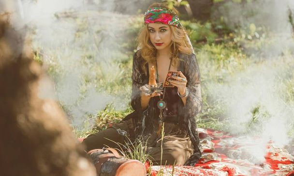 Zigeunerziel... Boho vrouw met tarotkaarten, kaarsen en magische bal op het veld, levensstijl, voorspellen, ideeën voor kostuum op Halloween - Foto, afbeelding