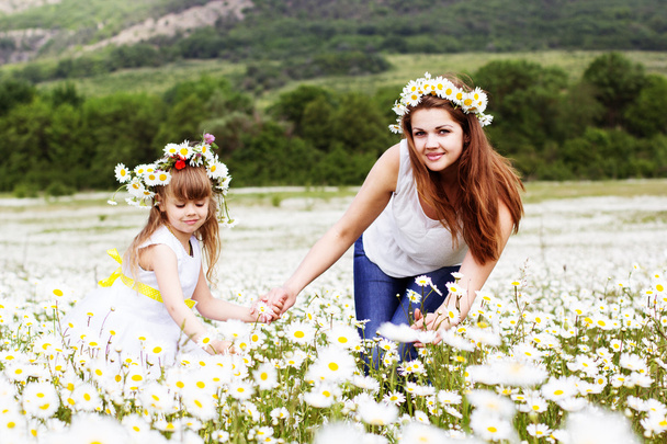 Mother with her child playing in camomile field - Foto, afbeelding