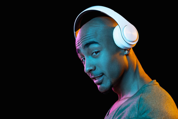 African-american young mans portrait on dark studio background in neon. Concept of human emotions, facial expression, youth, sales, ad. - 写真・画像