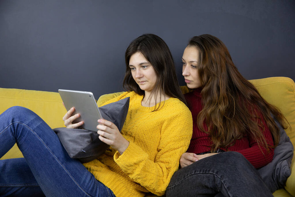 dos chicas bonitas hacen compras o pagos en línea utilizando la tableta Sofá de compras - Foto, imagen