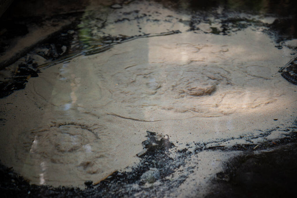 Primer plano de los manantiales subterráneos con agua clara. Muelles subterráneos cuando vienen del suelo a través de la arena de la playa levantándolos para formar un pequeño volcán - Foto, Imagen