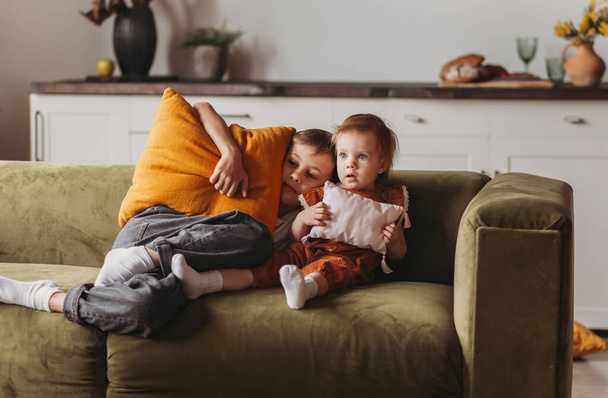Crianças irmão e irmã brincam com travesseiros no sofá na sala de estar - Foto, Imagem