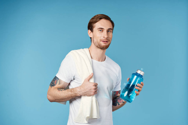 άνδρας σε λευκό t-shirt τατουάζ στα χέρια του νερό μπουκάλι fitness lifestyle - Φωτογραφία, εικόνα