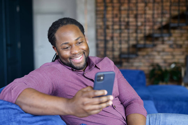 Happy African-American man with locks hair using smartphone - Foto, Imagem