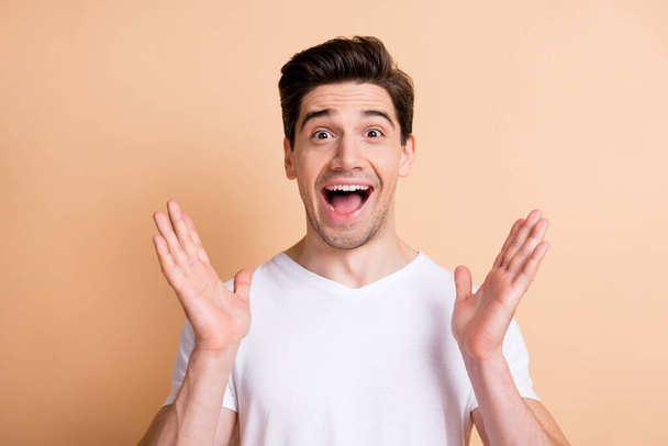 Photo of impressed amazed guy raise palms unbelievable discount isolated on pastel beige color background - 写真・画像