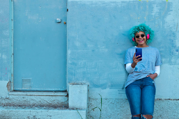 afro amerikaans meisje met mobiele telefoon en koptelefoon op de stad straat - Foto, afbeelding