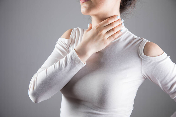 eine junge Frau hat Halsschmerzen auf grauem Hintergrund - Foto, Bild