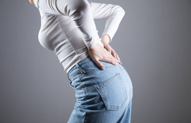 mladá žena bolí ledviny na šedém pozadí - Fotografie, Obrázek