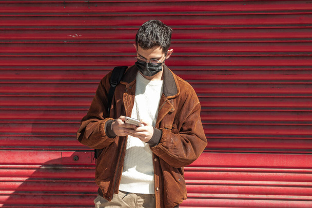 άνδρας με μάσκα και κινητό τηλέφωνο στο δρόμο - Φωτογραφία, εικόνα