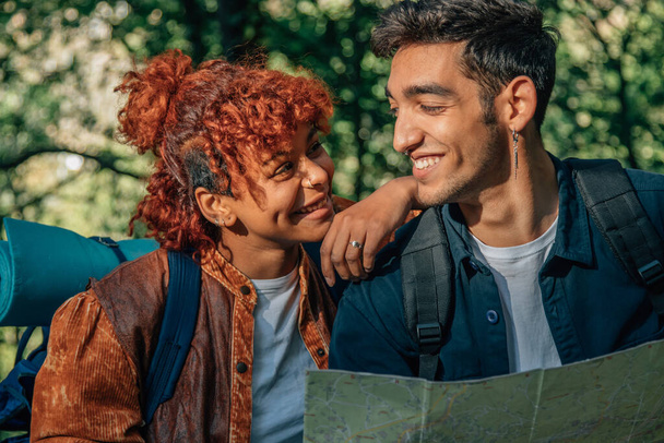 πολυπολιτισμικό νεαρό ζευγάρι με χάρτη και ταξιδιωτικό σακίδιο - Φωτογραφία, εικόνα