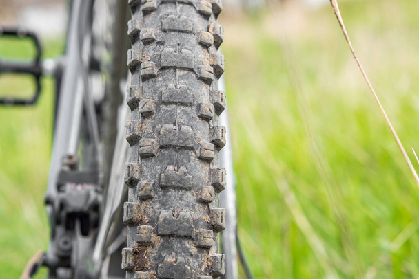 Rear view of a dirty mountain bike wheel that stands against a background of green grass. Selective focus. Healthy Lifestyle Concept - Fotografie, Obrázek