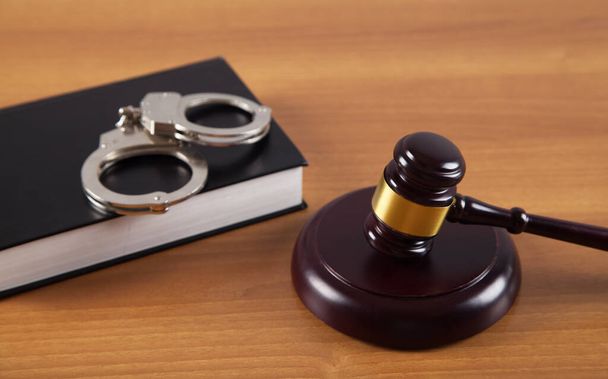 Молоток и наручники юридическая книга на деревянном столе. - Фото, изображение