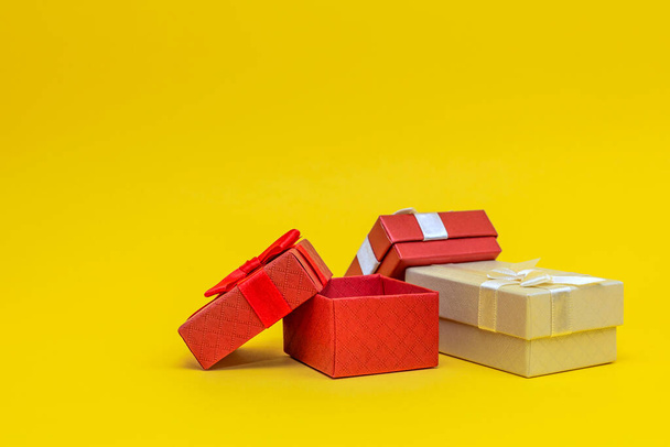 Подарочные коробки на желтом фоне. Красные подарочные коробки, открытая. Открытка для печати, баннер с местом для текста. - Фото, изображение