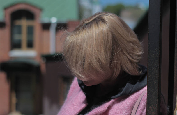 retrato de uma loira no perfil, com cabelo curto bonito, cercado por um fundo borrado com uma paisagem urbana  - Foto, Imagem