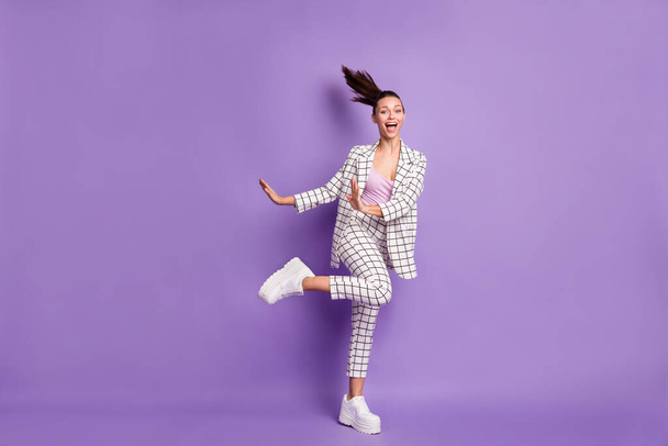 Full length photo of cheerful funky young woman dance fly hair good mood weekend isolated on purple color background - Photo, Image