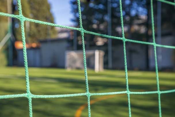 Πράσινο δίχτυ ποδοσφαίρου σε ένα γκολ. Ποδόσφαιρο κόμβους. Θολή θέση στόχου στο παρασκήνιο - Φωτογραφία, εικόνα