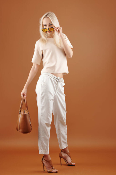 Elegant stylish young woman taking off sunglasses and looking at camera - Φωτογραφία, εικόνα
