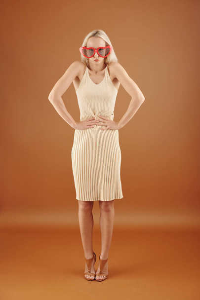 Slim pretty young woman making funny face when standing in plastic in heart shape sunglasses - Foto, Bild