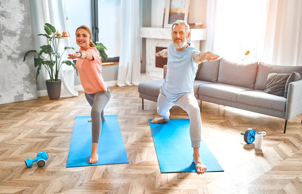 Spor, spor ve sağlıklı yaşam tarzı konsepti. Yetişkin bir çift evde egzersiz ya da yoga yapıyor. Karantinada nasıl sağlıklı kalınır?. - Fotoğraf, Görsel