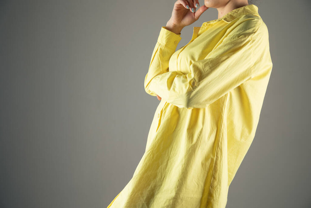 νεαρό κορίτσι που ποζάρει με κίτρινο πουκάμισο σε γκρι φόντο - Φωτογραφία, εικόνα