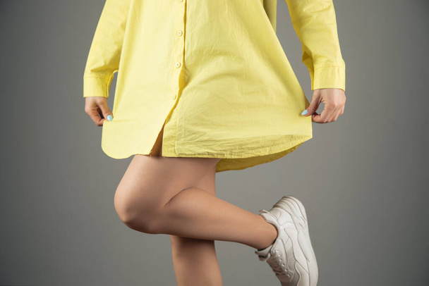 young girl posing in a yellow shirt on a gray background - Foto, Imagen