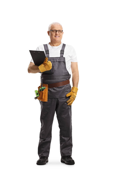 Full length portrait of a repairman with a tool belt holding a clipboard isolated on white background - Photo, image