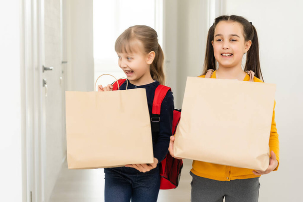 dos niñas de la escuela con mochila y paquetes de entrega manos en fondo blanco - Foto, imagen