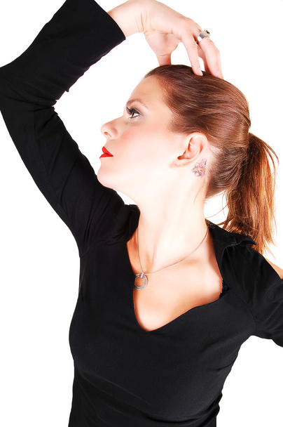 jonge licht rood donkerharige vrouw in een zwarte jurk staande in de studio voor witte achtergrond, heeft haar rechterhand op haar hoofd en denken. - Foto, afbeelding