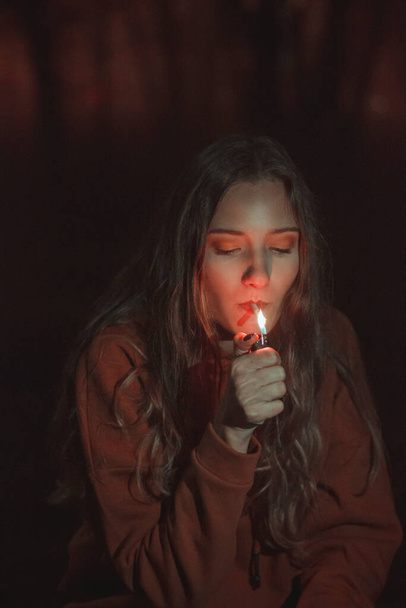 Ένα όμορφο κορίτσι ανάβει τσιγάρο τη νύχτα. Vintage φωτογραφίες  - Φωτογραφία, εικόνα