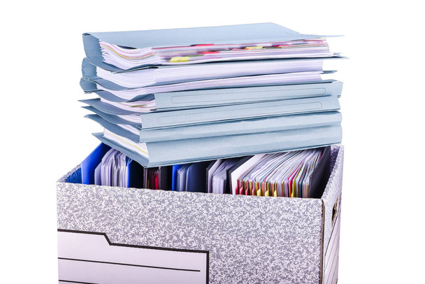 Dokumenty i foldery plików są umieszczone w papierowym pudełku i stos dodatkowych folderów plików na górze. Izolacja - Zdjęcie, obraz