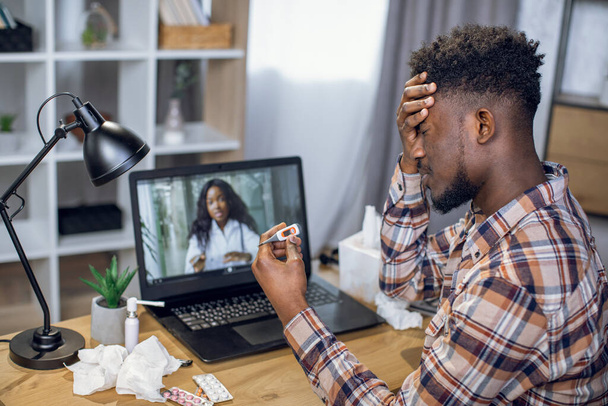 アフリカの男は医者とのオンライン会話のためにラップトップを使用して - 写真・画像