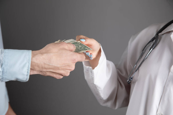 doctor takes money on a gray background - Foto, Bild