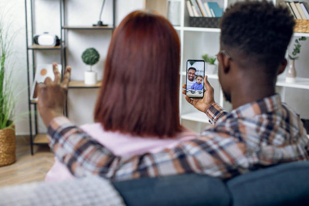 Multicultural couple using mobile for video call with family - Fotó, kép