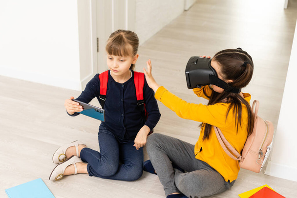 Kokeilen uutta teknologiaa. Pieni koulutyttö yllään iso VR lasit on vaikuttunut pelaa virtuaalisia pelejä koulussa. - Valokuva, kuva