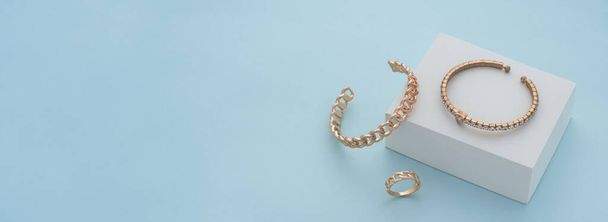 Panoramic shot of golden bracelets and ring on white box on blue background with copy space - Photo, Image