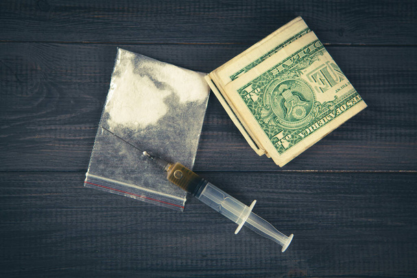 polvere bianca in una borsa, siringa e denaro su un tavolo di legno grigio. il concetto di tossicodipendenza - Foto, immagini