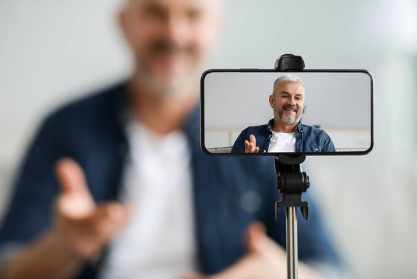 Handy-Bildschirm mit fröhlichem Senioren-Blogger - Foto, Bild