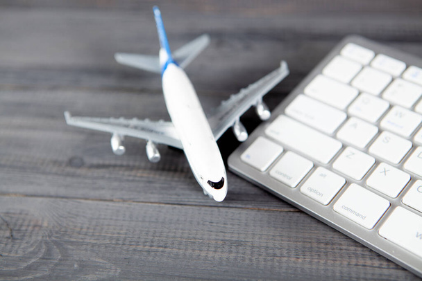 plane and keyboard. online purchase of airline tickets on a gray wooden table - Photo, Image
