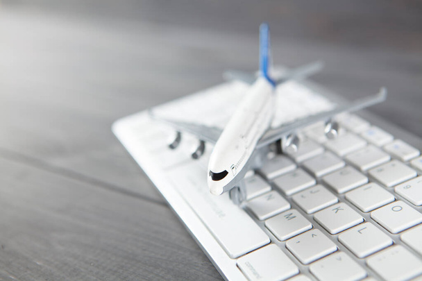 plane and keyboard. online purchase of airline tickets on a gray wooden table - Foto, immagini