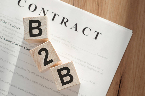 Word B2B on wooden cubes on contract documents background. - Fotografie, Obrázek