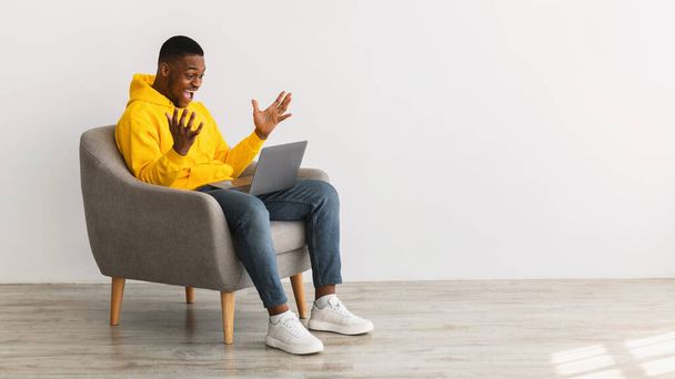 Hombre africano emocionado con el ordenador portátil celebrando Noticias, Fondo gris, Panorama - Foto, Imagen