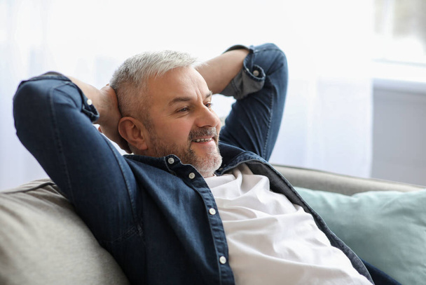 Onnellinen parrakas vanhempi mies rentoutuu sohvalla kotona, lähikuva - Valokuva, kuva