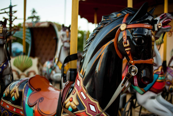 Retro kolotoč, černý kůň. Starý dřevěný kolotoč. Kolotoč Koně na vintage, retro karneval veselá procházka. Detailní záběr barevného kolotoče s koňmi. - Fotografie, Obrázek