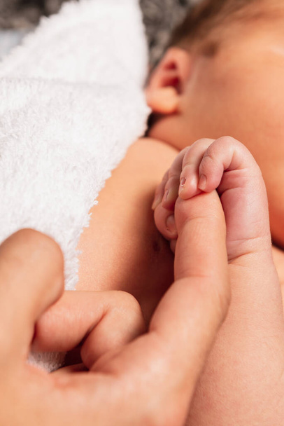 unrecognizable newborn baby holding the hand of his unrecognizable father. paternity. detail of hands - Photo, Image