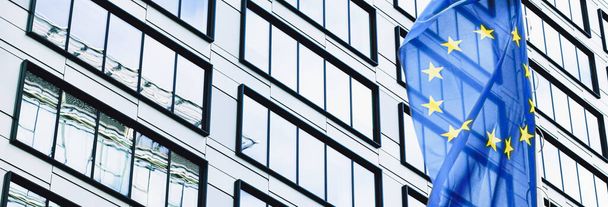 Drapeau de l'Union européenne agitant devant un immeuble de bureaux d'entreprise moderne, symbole du Parlement européen, de la Commission et du Conseil - Photo, image